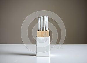 Set of white kitchen knives in a wooden knife block on table , isolated on a gray