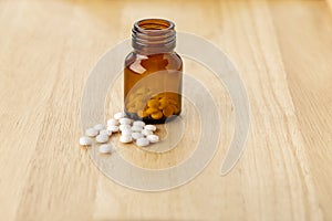 A set of white pills lying by a glass bottle of medicine