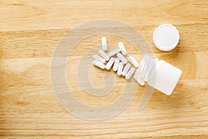 Set of white pills are by the medicine bottle