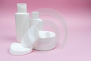 Set of white plastic cosmetic bottles and jar mock-up with cotton pads.