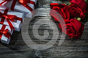 Set of white present boxes bunch of red roses on wooden board