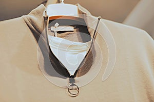 A set of a white T-shirt and a beige polo with a zipper collar hangs on a white hanger in a clothing store. Shopping