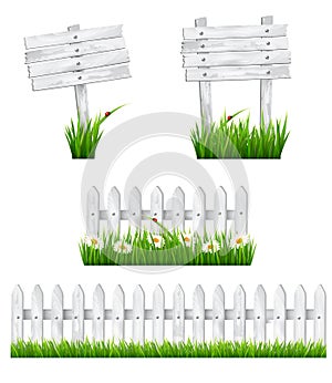 Set of white wooden signs and a fences with grass.