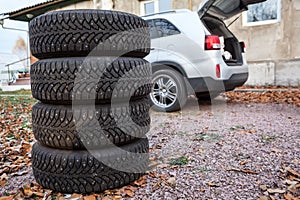 Set of winter wheels and tyres ready for changing near car, copyspace