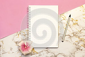 Set of women`s accessories desk - notebook with pen, flower on pink marble background. Workspace table for beauty blogger`s. Fla