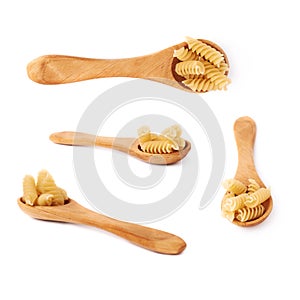 Set of wooden spoon filled with dry rotini pasta over isolated white background