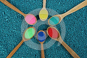 Set of wooden spoons with colored sand on blue stones