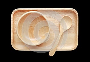 Set of wooden tray, bowl and spoon isolated on black background. Top view