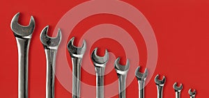 Set of worn and used wrenches lined up on red background