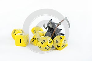 Set of yellow dices for rpg, dnd, tabletop or board games on light background. Figure of a skeleton with a sythe photo