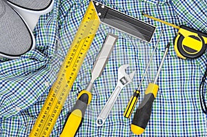 Set of yellow tools on checkered shirt and sneakers top view. men`s hobby flat lay concept