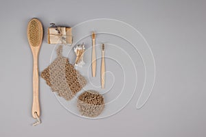 Set of zero waste bathroom essentials on grey background - bamboo toothbrushes, cotton buds, wooden body brush, jute washcloth and