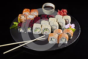 Seth sushi on a black background.Menu of the Japanese restaurant. Several sushi lined on a plate with bamboo sticks and soy sauce