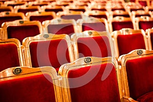 Sets on an empty theatre, taken with selective focus and shallow depth of field. Empty vintage red seats with numbers, teather cha photo