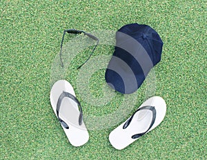 Sets of hat,sunglasses and flip flops on green grass