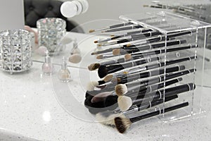 Sets of makeup brushes and cosmetics on a bright workplace of a make-up artist.