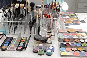 Sets of makeup brushes and cosmetics on a bright workplace of a make-up artist.