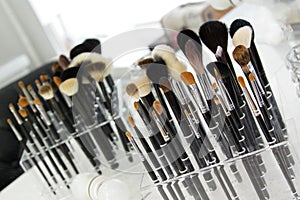 Sets of makeup brushes and cosmetics on a bright workplace of a make-up artist.