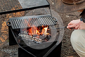 Setting the campfire in a portable foladble firepit for a camp cooking