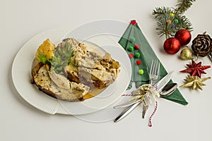 Setting christmas or new year table with baked slices of turkey meat,elegant paper napkin and christmas ornaments.