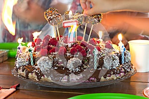 Setting fire to a candles on a childrens birthday cake, hands with burning matches in bokeh.