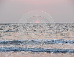 Setting Red Sun at Horizon over Sea at Payyambalam Beach, Kannur, Kerala, India