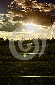 The setting sun in the evening over the railway tracks, the reflection of the light can be seen