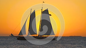 Setting Sun Over Florida Keys Ocean Closeup Sailboat Sails Through it. Orange sunset behind ocean horizon sailboat