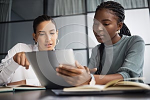 Setting their plans in place. two businesswomen working together on a digital tablet in an office.