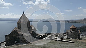 Sevan Monastery. Buildings, Lake Sevan, mountains, rocks, grass, sky, people