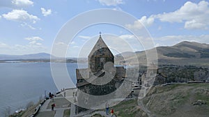 Sevan Monastery. Buildings, Lake Sevan, mountains, rocks, grass, sky, people