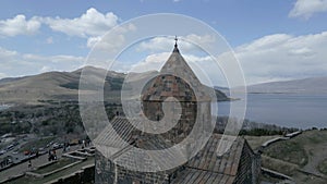 Sevan Monastery. Buildings, Lake Sevan, mountains, rocks, grass, sky, people