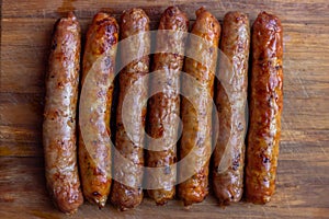 Seven appetizing toasted sausages with turkey lie on a wooden board