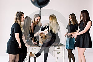 Seven beautiful young women celebrate hen-party and having fun on white background. Best friends wearing black stylish