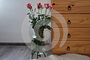 Seven bouquets of roses in a vase built with wooden dressers.