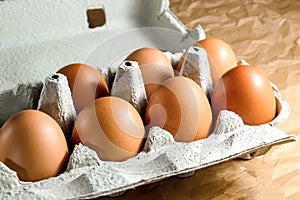 Seven brown chicken eggs in a carton paper packaging on a kitchen table. Eggs for breackfast. Healthy eating and food Ingredients photo