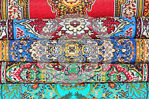 Seven carpets lie in rouleau on each other