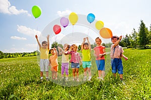 Seven children with balloons in green field