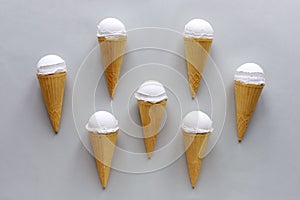 Seven cornets with vanilla ice cream on grey