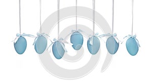 Seven Easter blue eggs hanging on ribbons a small bow isolated on a white background.