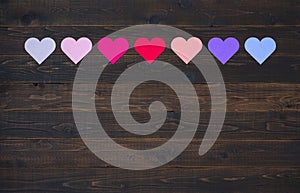 Seven Hearts in Various colors on rustic wood board background