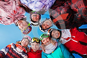 Seven laughing friends in circle wearing goggles