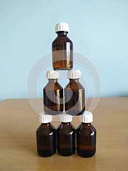 Seven medical glass brown bottles with white caps stand in a tower