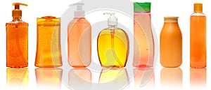 Seven orange Plastic Bottles With Shampoo, Liquid Soap, Shower Gel. Isolated on white background with reflection.