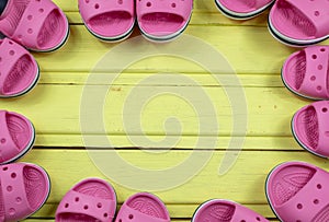 Seven pairs of beach children`s shoes on a yellow wooden background. Close-up.