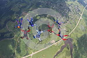 Seven skydivers are in the blue sky.