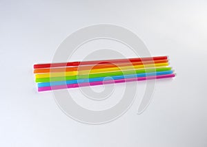 Seven straws of rainbow colors lie on a light gray background. Bright colors. The colors symbolize the concept of