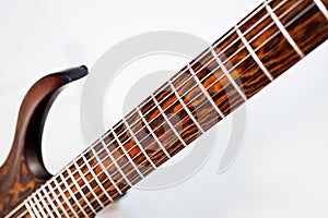 Seven-string electric guitar made of dark wood. Shot on a white background. Background for music and creativity