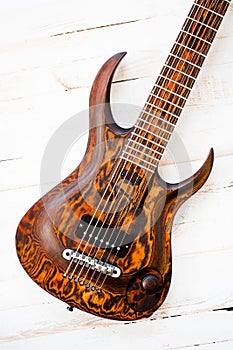 Seven-string electric guitar made of dark wood. Shot on a white background. Background for music and creativity