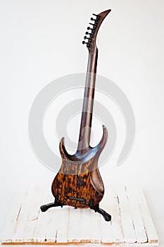 Seven-string electric guitar made of dark wood. Shot on a white background. Background for music and creativity